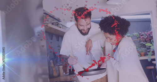 Image of hearts over happy diverse couple cooking