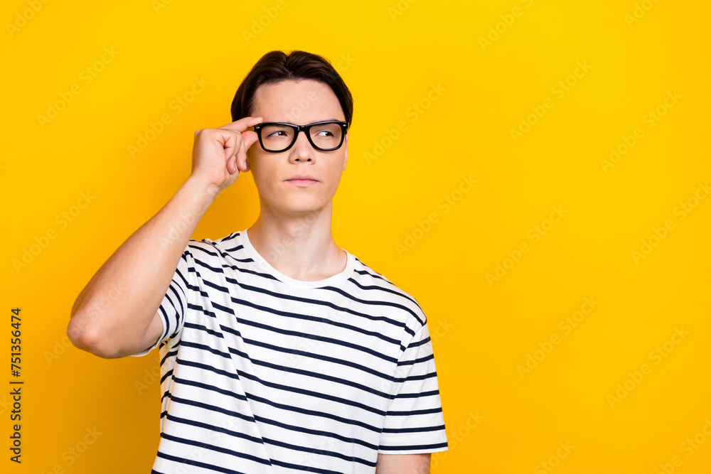 Portrait of clever serious student wear stylish t-shirt touch eyewear suspiciously look empty space isolated on yellow color background Portrait of clever serious student wear stylish t-shirt touch eyewear suspiciously look empty space isolated on yellow color background