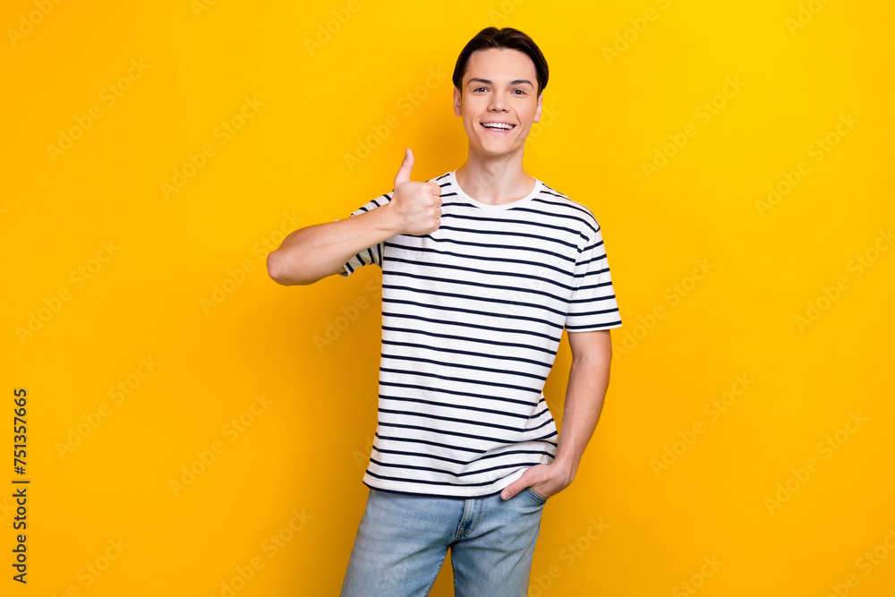 Photo of satisfied guy with stylish hairdo dressed striped t-shirt showing thumb up approve nice work isolated on yellow color background Photo of satisfied guy with stylish hairdo dressed striped t-shirt showing thumb up approve nice work isolated on yellow color background