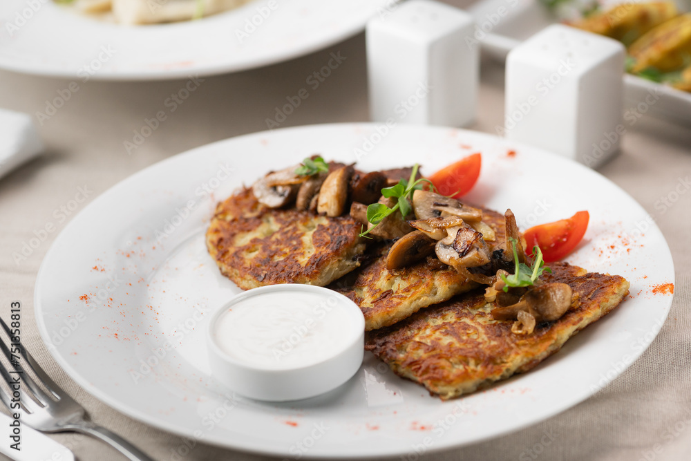 Potato pancakes with mushrooms. Potatoes pancakes on white plate with sour cream. Copy space Potato pancakes with mushrooms. Potatoes pancakes on white plate with sour cream. Copy space