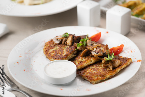 Potato pancakes with mushrooms. Potatoes pancakes on white plate with sour cream. Copy space