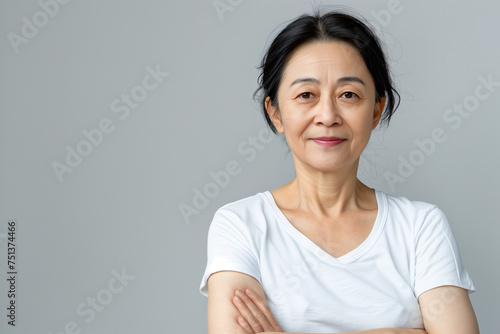 Elegant Mature Asian Woman in White Shirt with Confident Smile and Arms Crossed, Embodying Timeless Grace