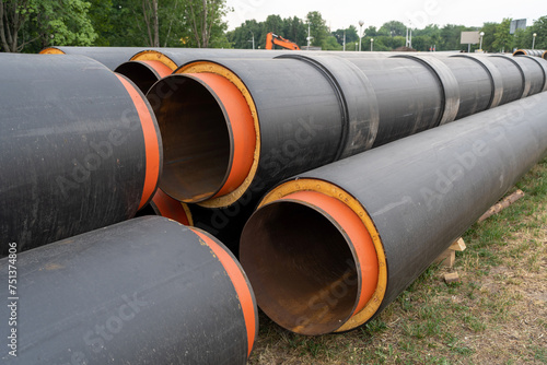 Steel pipe with heat insulation. New black insulated steel pipes at municipal construction site outdoors. Heating main district pipeline renewal or reconstruction.