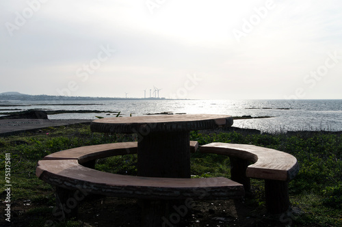 View of the round table and benches against the seaside in the sunny afternoon