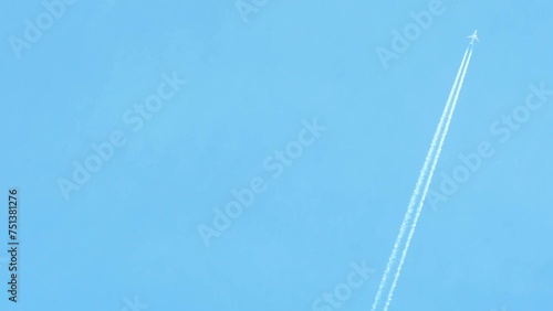 A passenger plane flies against a background of a blue sky without clouds.A long white trail remains behind the plane and gradually dissolves.Travel themed background with empty space for information