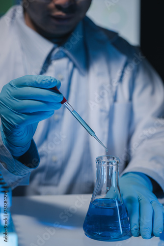 A researcher is carefully studying the liquid contained in a test tube because it is an important area of research, A scientist is using a tool to conduct a scientific experiment on liquids.