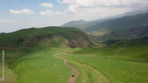 Drone: flies behind a car along the valley of the mountains of Kyrgyzstan