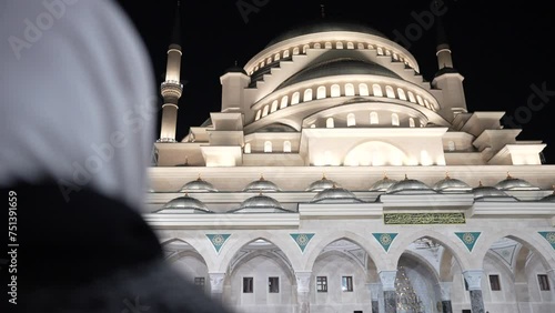 A young Muslim woman in a hijab looks with admiration at the minarets of the second largest mosque in Türkiye. photo