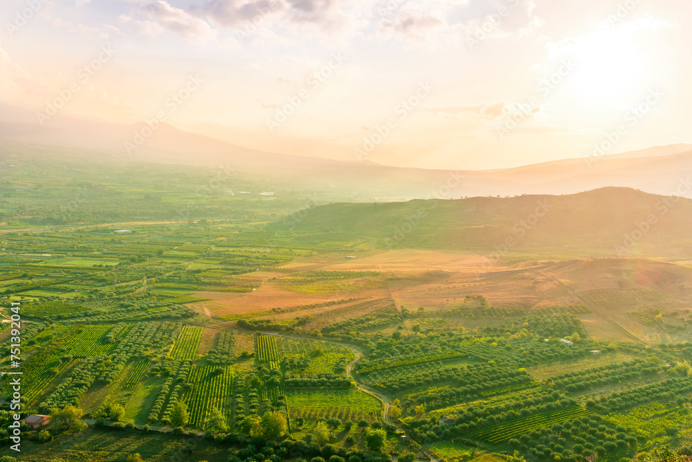 Obraz premium scenic rustic landscape with green hills and farms in a mountain valley during colorful cloudy sunset