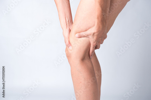 Fototapeta Naklejka Na Ścianę i Meble -  A person with a knee injury is holding their knee. Concept of pain and discomfort