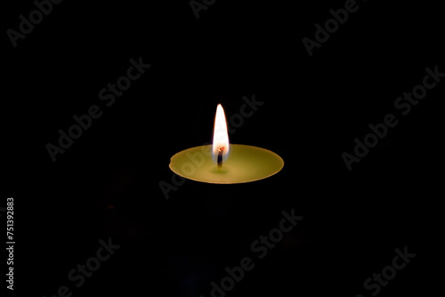 Tea candle burning flame on a black background isolated