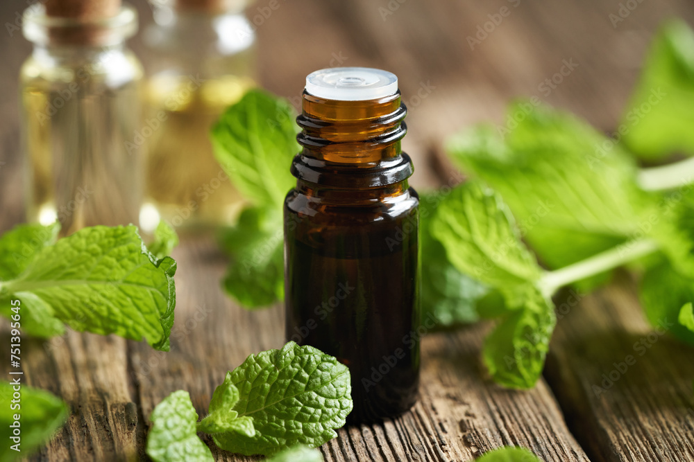 A brown bottle of aromatherapy essential oil with fresh peppermint plant A brown bottle of aromatherapy essential oil with fresh peppermint plant