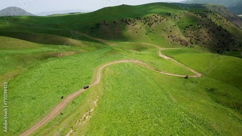 Drone: flies behind a car along the valley of the mountains of Kyrgyzstan