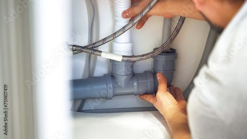 Close up plumber hands repair plumbing pipes in kitchen sink. Removing blockage clog in drain pipe. Replacement of plumbing pipes photo