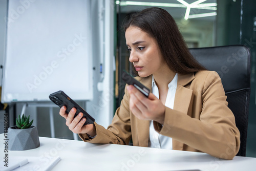 disappointed and deceived woman inside office at workplace, businesswoman holding bank credit card and phone, received error and rejected money transfer.