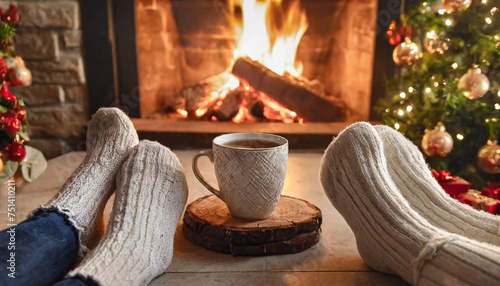couple feet by the cozy fireplace. Man and Woman relaxes by warm fire with a cup of hot drink and warming up her feet. Close up on feet. Winter and Christmas holidays concept