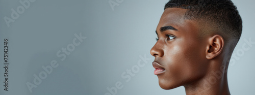 Side-profile image showcasing a sharply executed fade haircut, highlighted against a light gray background to accentuate the hairstyle's details. This composition focuses on elegance of the hairstyle