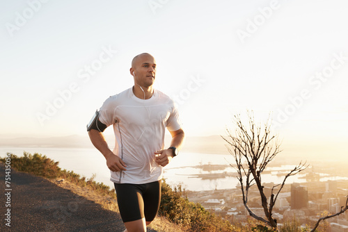 Athlete, man and running in road with music for sport, exercise and fitness for competition or marathon in nature. Runner, person and workout with wellness, seaside and earphones for cardio in Mexico