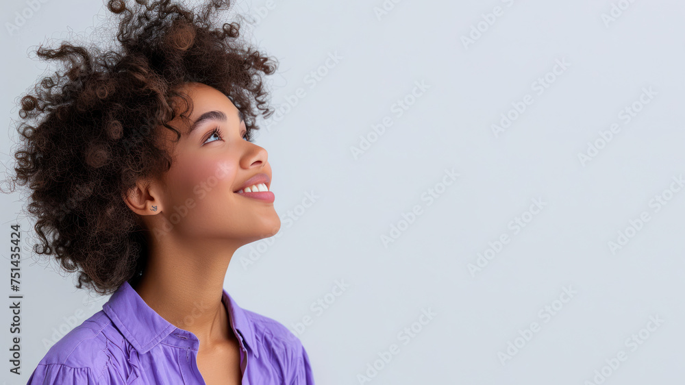 Afro woman wearing purple shirt smile looking up isolated on gray Afro woman wearing purple shirt smile looking up isolated on gray