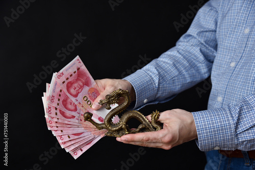 Businessman holding banknotes in his hand. Chinese RMB cash and symbolic dragon.