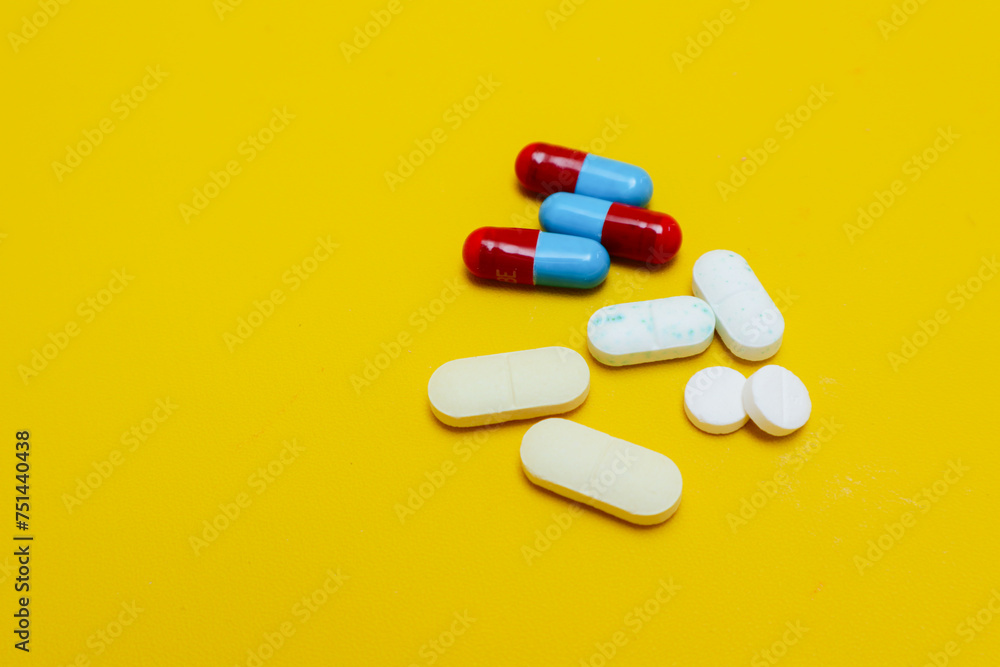 photo of medicine capsules and tablets isolated on yellow background photo of medicine capsules and tablets isolated on yellow background