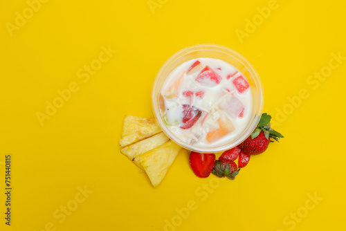 Fototapeta Naklejka Na Ścianę i Meble -  es buah or sup buah is indonesian fruit cocktail ice desert, contains strawberry, pineapple, and other tropical fruits mixed with ice cube, and condensed milk. isolated on yellow background.