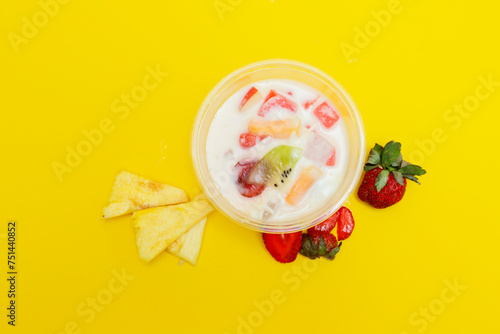 es buah or sup buah is indonesian fruit cocktail ice desert, contains strawberry, pineapple, and other tropical fruits mixed with ice cube, and condensed milk. isolated on yellow background.