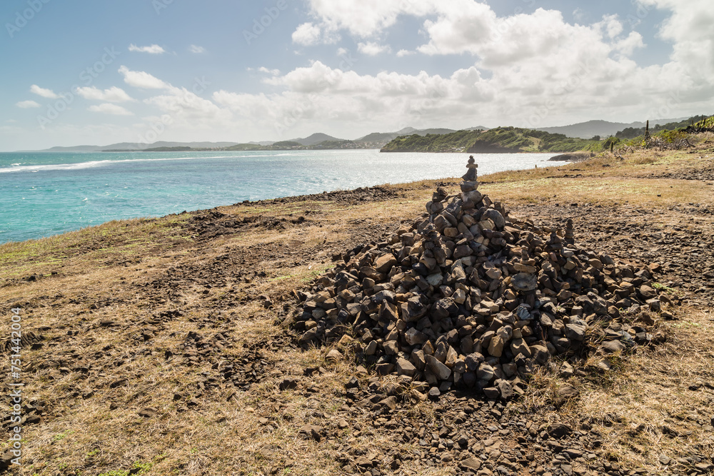 Panorama côtier lumineux avec un grand cairn devant une baie marine, et de petites collines. Pointe du Vauclin, Martinique Panorama côtier lumineux avec un grand cairn devant une baie marine, et de petites collines. Pointe du Vauclin, Martinique