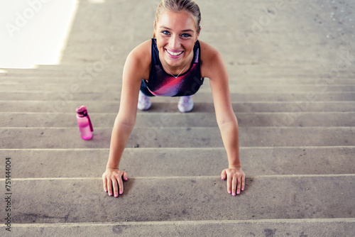 Young woman doing push-ups on stairs. Urban fitness woman workout doing torso elevated push ups on urban stairs. Motivated strong female athlete training hard.
