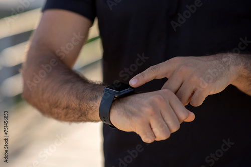 man's hands using smartwatch fitness tracker during workout outside, closeup © Prostock-studio
