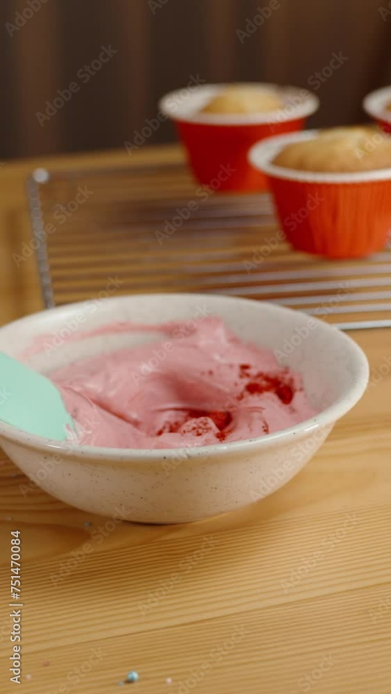 The confectioner adds red powdered food coloring to the cream. Cupcakes on the table. The confectioner adds red powdered food coloring to the cream. Cupcakes on the table.