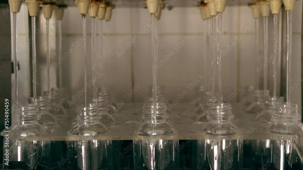 The process of filling clean drinking water into water bottles by an automatic drinking water filling machine in a drinking water production factory The process of filling clean drinking water into water bottles by an automatic drinking water filling machine in a drinking water production factory