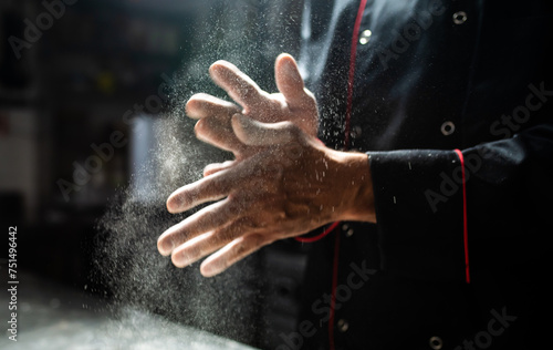 Chef clapping flour off hands in dramatic kitchen light © Minerva Studio