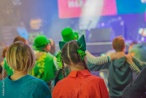 Rear view of two young women in green outfits and decorations at Saint Patrick's Day party celebration