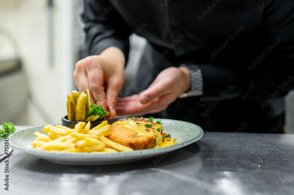 chef cooking Fried Wiener schnitzel from veal topside with French fries and cheese sauce on kitchen
