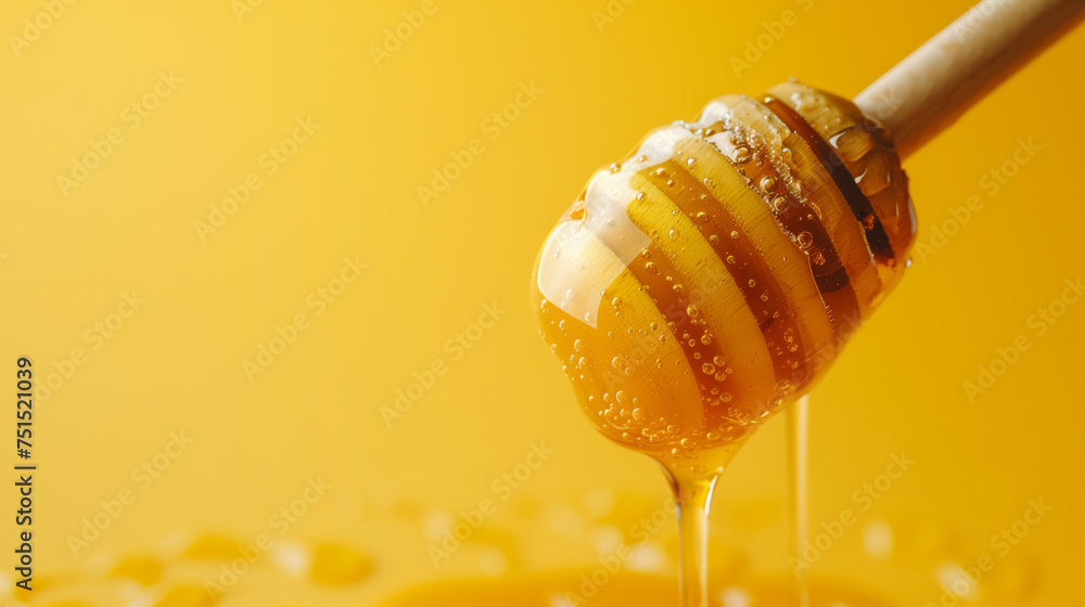 Honey on a wooden spoon flows onto a yellow background with space for your text Honey on a wooden spoon flows onto a yellow background with space for your text