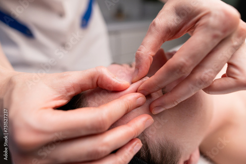 Close-up shot of a woman s head doing a facial massage on a treatment table. Therapist applying pressure with thumbs on forehead