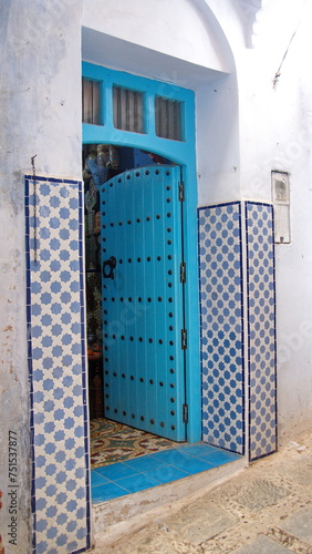 Blue, wooden doorway surrounded by tile in the medina, in Chefchaouen, Morocco © Angela