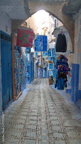 Paintings hanging in front of shops in an alley in the medina, in Chefchaouen, Morocco © Angela