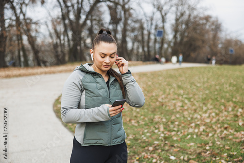 Woman Using Cell Phone During an Outdoor Workout in the Park © milanmarkovic78