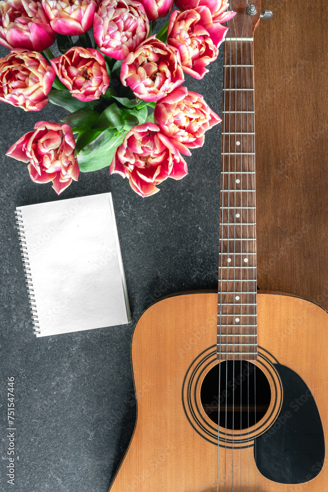 Fototapeta premium Top view, acoustic guitar, notepad and tulips on the table.