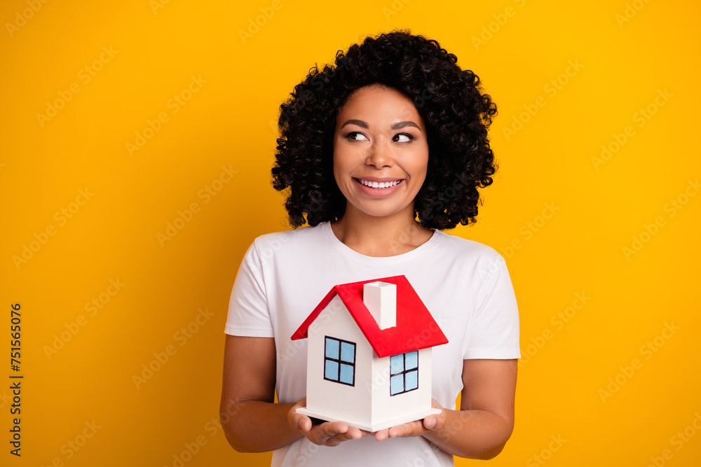 Photo of optimistic woman dressed white t-shirt hold house look at real estate offer empty space isolated on yellow color background Photo of optimistic woman dressed white t-shirt hold house look at real estate offer empty space isolated on yellow color background