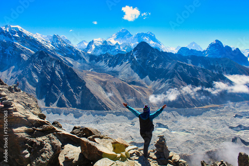 A Trekker celebrates reaching the summit of 5350 m high Gokyo Ri providing grand stand views of the Highest mountain peaks on Earth - Everest,Lhotse,Makalu, Cho Oyu and the Ngozumpa glacier in Nepal photo