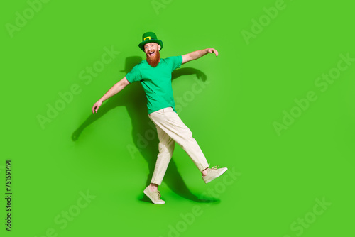 Full length profile portrait of excited cheerful guy dance walk empty space isolated on green color background