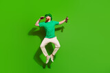 Full size portrait of crazy guy jump hold glass beer bottle empty space ad isolated on green color background