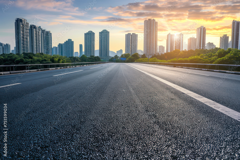 Asphalt highway and skyline with modern buildings at sunset.