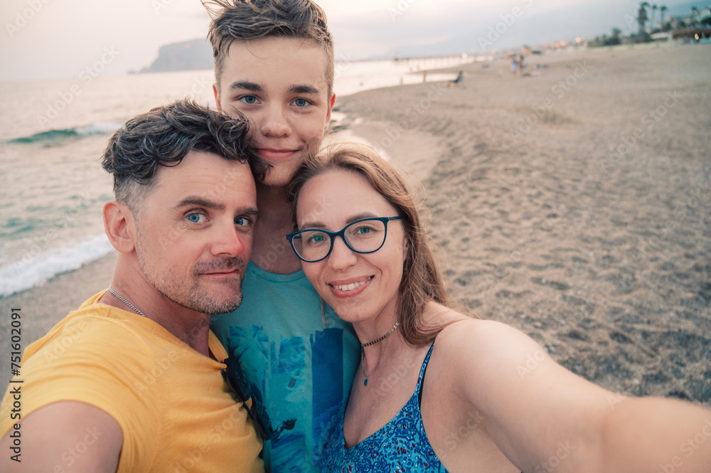 Happy family taking a photo on a beach at the sea in Alanya city, Turkey. Travelling or vacation concept