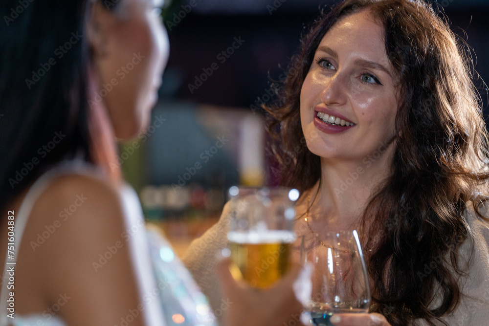 two girls in sexy dress are drinking and dancing at bar. Dance party with group people dancing . Women and men have fun and drinking martini cocktail in night club.