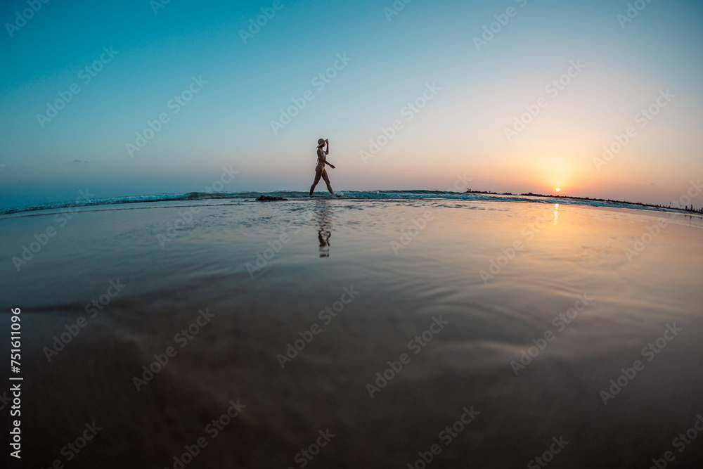 Happy girl walking on the beach at sunset. silhouette of a woman walking along the beach. relaxation on the beach.