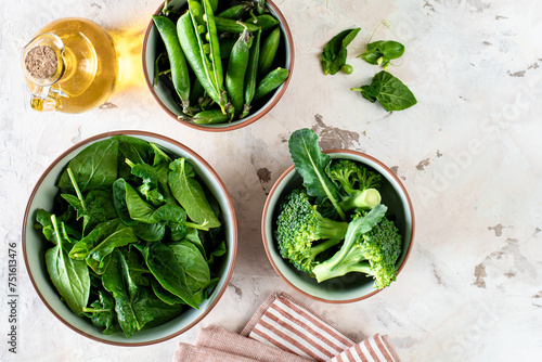 Fresh spinach leaves, green peas, broccoli in a bowl, top view